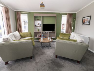 A living room with two sofas and a round coffee table in front of a TV unit at Hazelwood 2 Pinewood near Lyme Regis