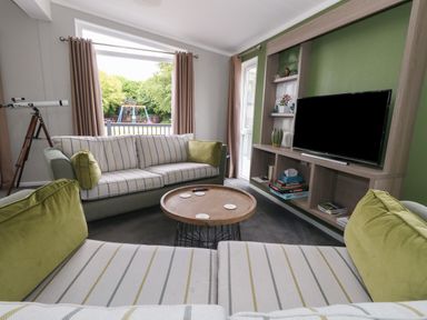 A living room with striped sofas green cushions and a round coffee table at Hazelwood 2 Pinewood near Lyme Regis