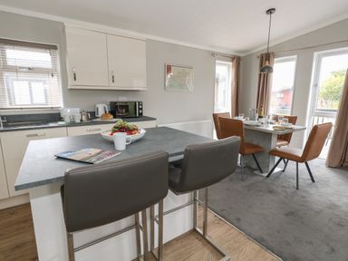 A kitchen and dining area with an island countertop and bar stools at Hazelwood 2 in Pinewood near Lyme Regis