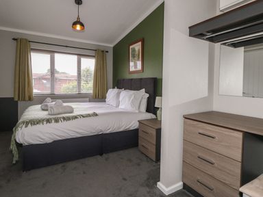 A bedroom with a double bed bedside table and chest of drawers at Hazelwood 2 Pinewood near Lyme Regis
