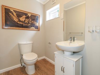 A bathroom with a toilet a sink with cabinet a mirror and a framed map on the wall at Hazelwood 2 Pinewood near Lyme Regis