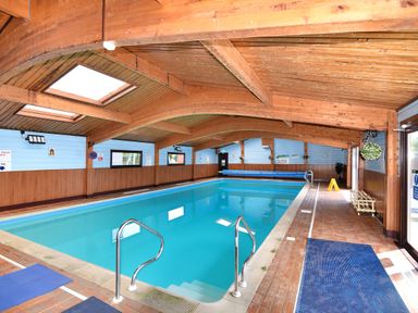 An indoor swimming pool with wooden ceiling and blue walls at Hazelwood 2 Pinewood near Lyme Regis
