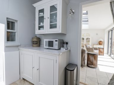 A kitchen with a microwave and cupboard at 8 Gloucester Street