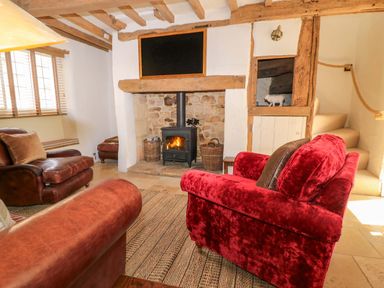 A living room with a fireplace and wooden beams at 8 Gloucester Street in Winchcombe