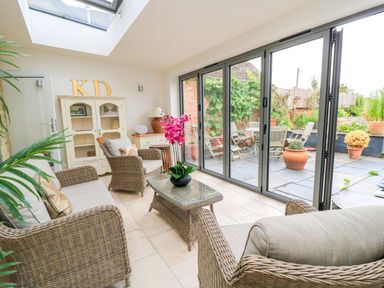 A conservatory with seating and a view of a garden at 8 Gloucester Street Winchcombe