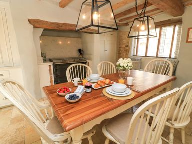 A kitchen with a dining table and breakfast items at 8 Gloucester Street Winchcombe