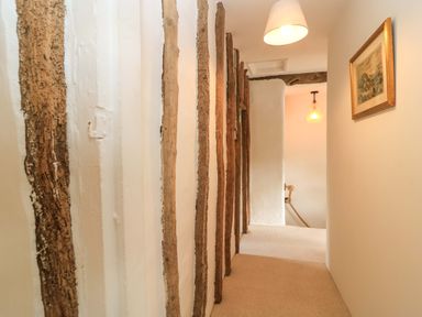 A hallway with wooden beams and light fixtures at 8 Gloucester Street Winchcombe