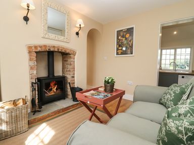 A living room with a fireplace a sofa and a small table at The Alms House East in Forthampton near Tewkesbury