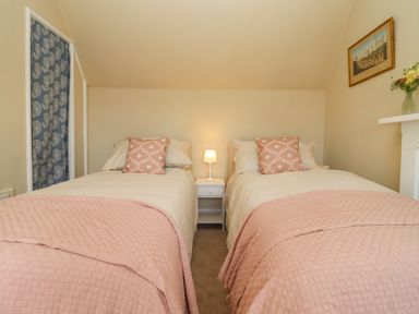 A bedroom with two single beds separated by a bedside table with a lamp at The Alms House East in Forthampton near Tewkesbury