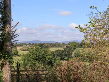 A countryside landscape with trees fields and mountains in the distance at The Alms House East in Forthampton near Tewkesbury