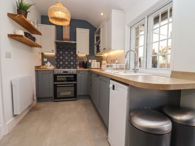 A kitchen with stove oven cabinets sink dishwasher and trash bins at The Alms House East in Forthampton near Tewkesbury
