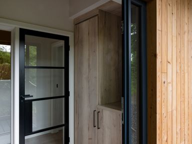 A corner with a wooden cabinet and a glass door with black frames at The Lookout in Longridge