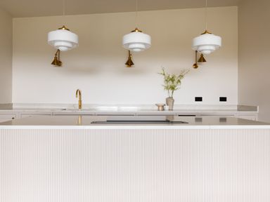 A kitchen island with a cooktop faucet and three pendant lights above at The Lookout in Longridge