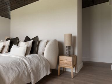 A bed with multiple pillows and a wooden nightstand with a lamp in a bedroom at The Lookout in Longridge