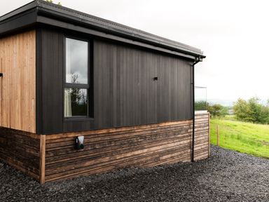 Exterior corner view of a building with black and natural wood paneling and a window at The Lookout in Longridge
