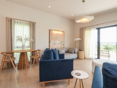 A living room with blue chairs a round wooden table with chairs and a grey corner sofa at The Lookout in Longridge