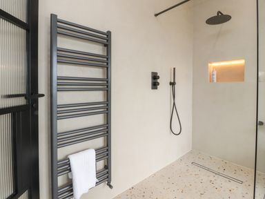 A bathroom shower area with a wall-mounted towel rack a rainfall showerhead handheld shower and a recessed shelf at The Lookout in Longridge