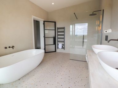 A bathroom with a freestanding bathtub double sinks a glass shower and a black towel radiator at The Lookout in Longridge