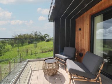 A balcony with two chairs and a round table overlooking a green field at The Lookout in Longridge