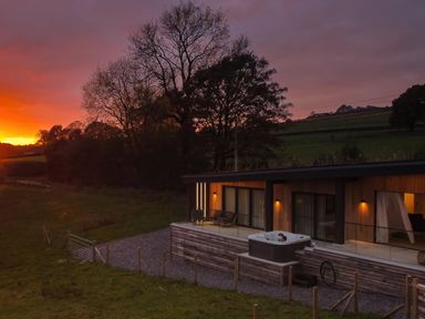 A modern house with a hot tub on the patio near trees at sunset at The Lookout in Longridge