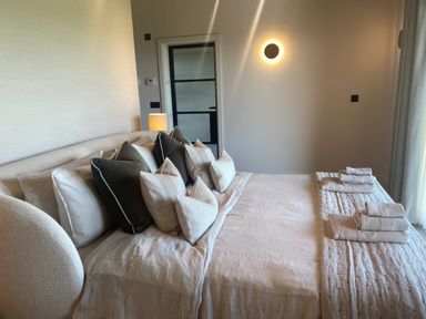 A bedroom with a bed covered in pillows and folded towels on the end at The Lookout in Longridge