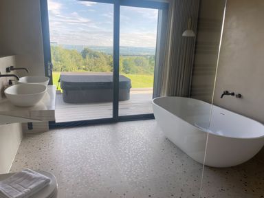 A bathroom with a freestanding tub double sinks and a glass door leading to a deck with a hot tub at The Lookout in Longridge