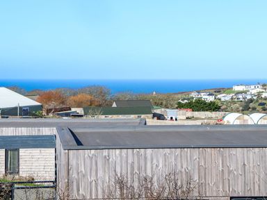 A landscape view of wooden buildings with rooftops overlooking the sea and distant houses at Bay View in Portreath
