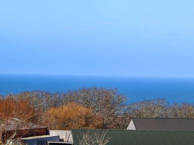 View of the ocean with trees and rooftops in the foreground at Bay View Portreath