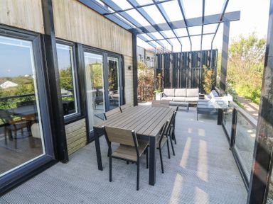 An outdoor patio with a dining table and chairs a seating area and plants at Bay View in Portreath
