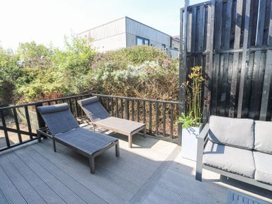 An outdoor deck with two lounge chairs a sofa and a planter with plants at Bay View in Portreath