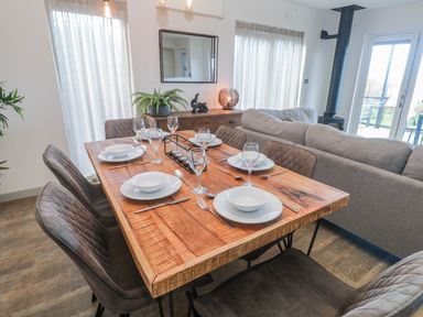 A dining room with a wooden table set for a meal at Bay View in Portreath