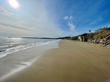 A sandy beach with ocean waves and wooden stairs leading down at The Warren M45 in Abersoch