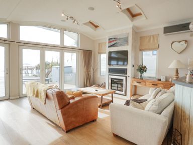 A living room with a leather sofa a fabric sofa wooden coffee table TV and fireplace at The Warren M45 in Abersoch