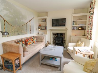 A living room with a sofa armchairs coffee table fireplace and bookshelf at Peartree in Colerne