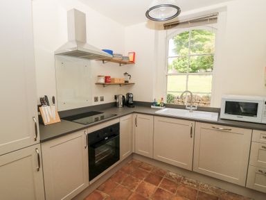 A kitchen with an oven microwave sink knives on a countertop and shelves with dishes at Peartree in Colerne