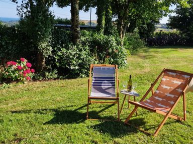 A garden with deck chairs and a table at Driftwood in Dartmouth