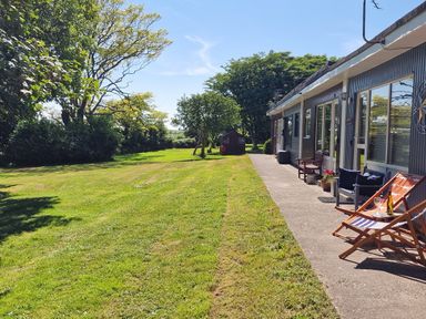 An outdoor area with grass, trees, chairs, and a shed at Driftwood in Dartmouth