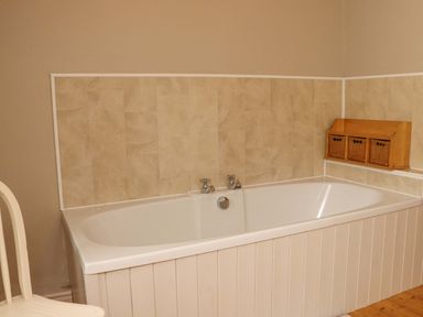 A bathroom with a bathtub and storage baskets at Orchard Barn Wexford