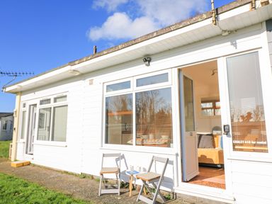 A white exterior of a house with two chairs and a small table outside near an open door at 418 Norton Park in Dartmouth