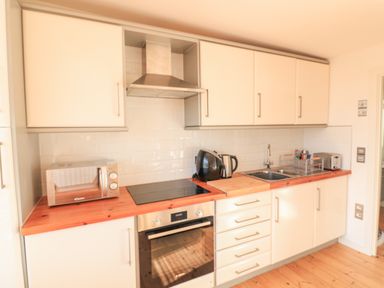 A kitchen with white cabinets wooden countertop a microwave oven stovetop sink kettle and toaster at 418 Norton Park Dartmouth