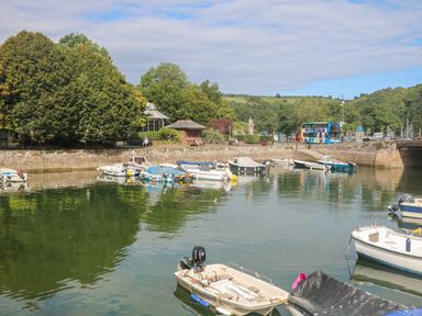 Boats moored on water near a stone quay with trees and a bus in the background at 418 Norton Park in Dartmouth