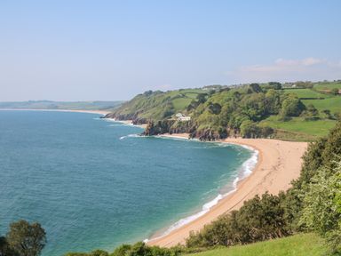 A coastal landscape with a sandy beach and green hills at 418 Norton Park in Dartmouth