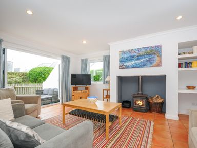 A living room with sofas a coffee table a burning wood stove and a television at Bryher in Trebetherick near Polzeath