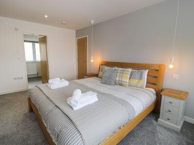 A bedroom with a wooden bed frame and patterned bedding with two bedside tables at Melin Y Plas in Llanaber