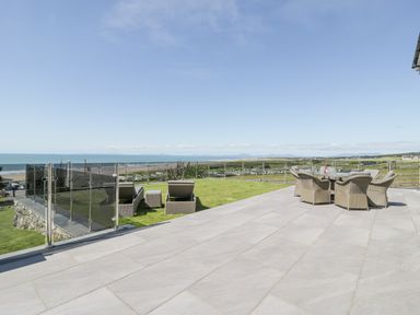 An outdoor terrace with patio furniture overlooking a coastal landscape at Melin Y Plas in Llanaber
