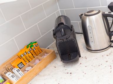 A kitchen counter with a coffee machine a kettle and a wooden tray with tea sachets sugar and coffee pods at Rowena in Mullion