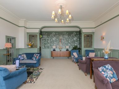 A sitting room with blue and purple armchairs and sofas a patterned rug and floral cushions at Rowena in Mullion