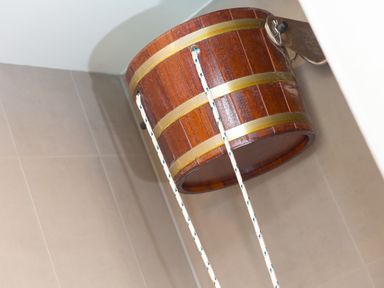 A wooden bucket shower mounted on a tiled wall at Rowena in Mullion