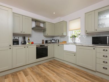 A kitchen with cabinets appliances and a window with a blind at Morwenna in Mullion