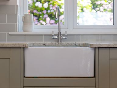 A kitchen sink with a silver faucet and a ceramic jug on the windowsill a garden can be seen through the window at Verity in Mullion